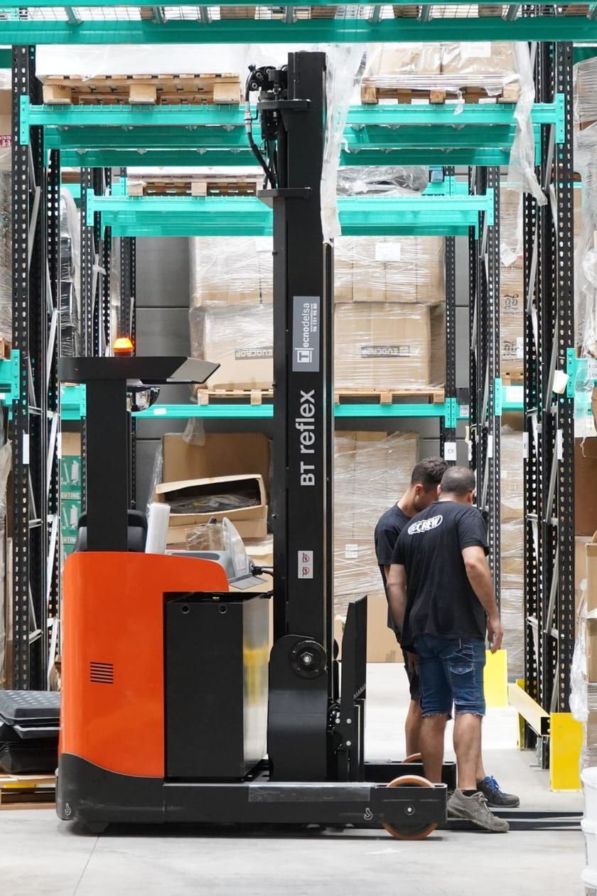 Magazijnmedewerkers en een reachtruck tussen hoge stellingen in een modern magazijn